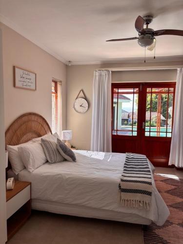 a bedroom with a bed and a clock on the wall at Cottage Hill in Gqeberha
