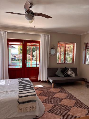 a bedroom with a couch and a ceiling fan at Cottage Hill in Gqeberha