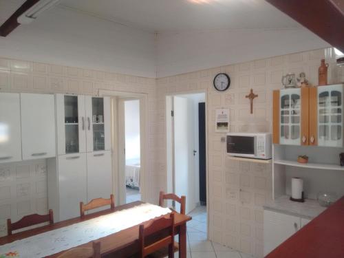cocina con mesa y reloj en la pared en Casa Dunas, en Florianópolis