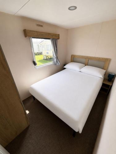 a white bed in a small room with a window at Seaview Holiday Rentals - Arizona pet friendly in Chestfield