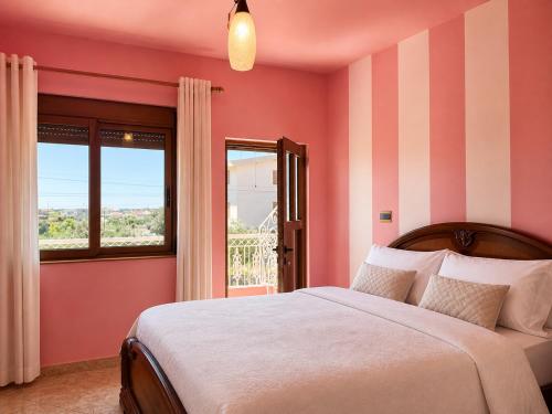 a bedroom with a bed with pink walls and a window at Fori Vodo in Divjakë