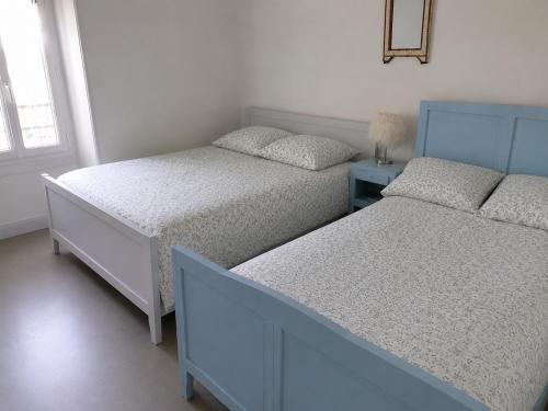 a bedroom with two beds and a mirror on the wall at La Parenthèse du Lot in Gramat