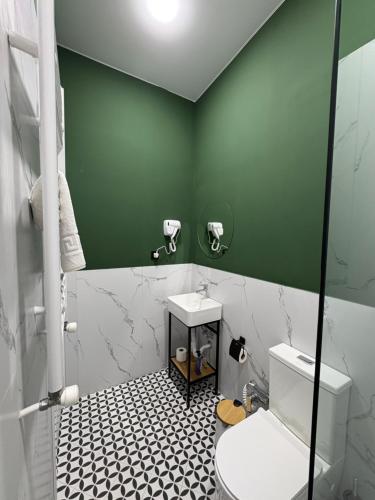 a green bathroom with a toilet and a sink at Polifonia Inn Borjomi in Borjomi