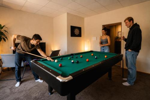 a group of three people playing a game of pool at Hang The Hat House in Valmiera