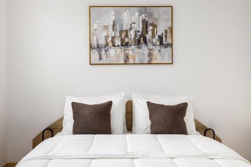 a bedroom with a white bed with a painting on the wall at Ourania Lofts and Suites in Thessaloniki