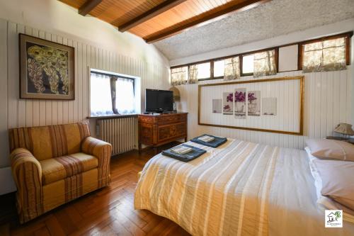 a bedroom with a bed and a chair and a television at Appartamenti La Menaresta quiet & relax near Bellagio in Magreglio