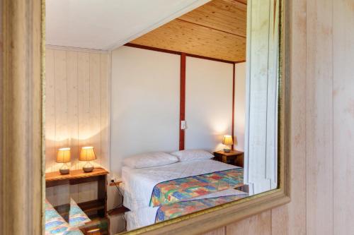 a reflection of a bedroom with a bed in a mirror at Chalet Le Tilleul in Salignac Eyvigues