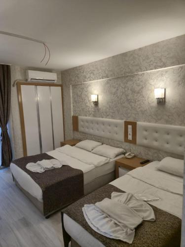a hotel room with two beds and two tables at Bulut Hotel in Pamukkale