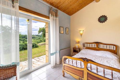 a bedroom with a bed and a large window at Gite Four De Mon Père in Salignac Eyvigues