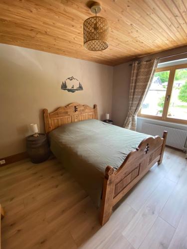 a bedroom with a wooden bed and a wooden ceiling at Gîte de la forêt in Mont-de-Vougney