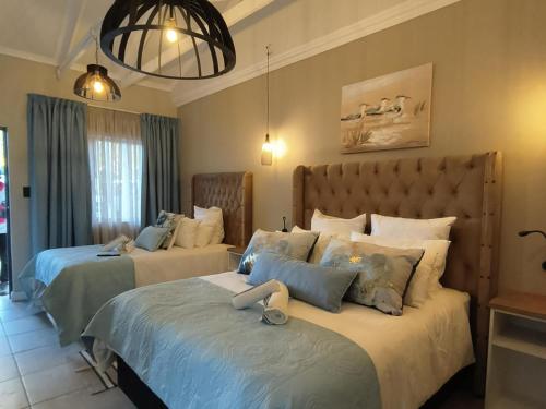 a bedroom with two beds and a chandelier at Bel-Air Guesthouse in Klerksdorp