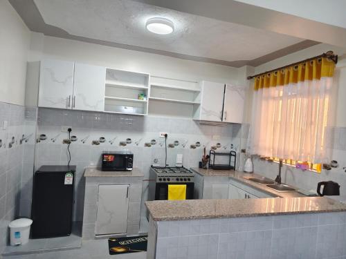 a kitchen with white cabinets and a stove top oven at GLOW Suites in Naivasha