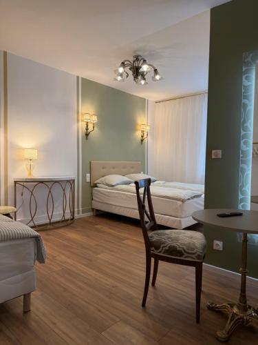 a bedroom with two beds and a chair and a table at Hôtel D’Artiste in Pierrefontaine-les-Varans