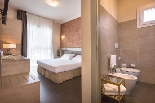 a hotel room with a bed and a bathroom at Hotel Helvetia in Lido di Jesolo