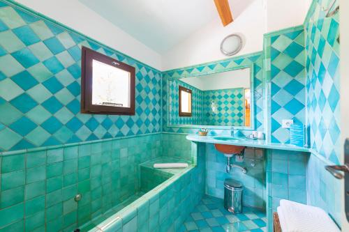 a blue tiled bathroom with a tub and a sink at La Ferme Rose-Hôtel de Charme in Moustiers-Sainte-Marie