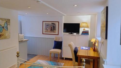 a living room with a desk and a television at The Studio at St Cleer in Chippenham