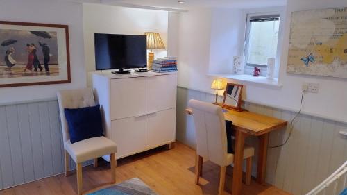 a living room with a desk and a television at The Studio at St Cleer in Chippenham