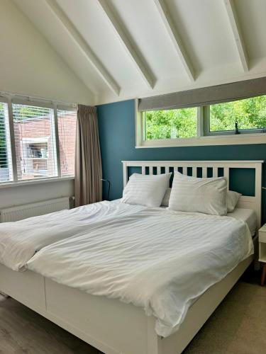 a bedroom with a large white bed with two windows at De Zeebries in Warmenhuizen