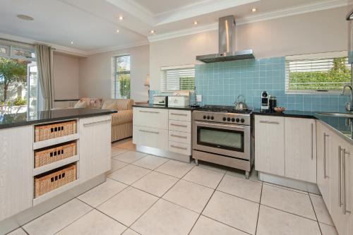 a kitchen with white cabinets and a stove top oven at Spatalla Holiday Homes in Kleinmond