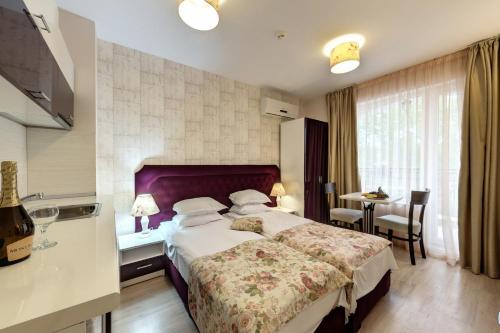 a hotel room with a large bed and a table at Avenue Deluxe Hotel in Sunny Beach