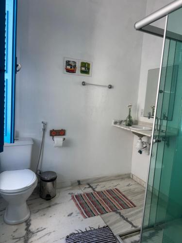 a bathroom with a toilet and a glass shower at Pousada santa rita in Paraty