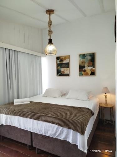 a bedroom with a large bed with white walls at Apartamento Gute Morro - Praça Central in Cairu