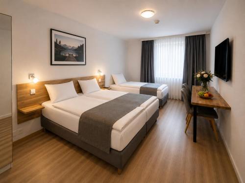 a hotel room with two beds and a desk at Hotel Drei Könige in Chur
