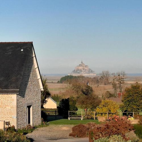 a house with a view of a castle in the distance at L'Aurore de la Baie, vue sur le Mont-Saint-Michel in Huisnes-sur-Mer