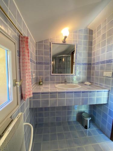 a blue tiled bathroom with a sink and a mirror at La chambre du Mazet in Fayence