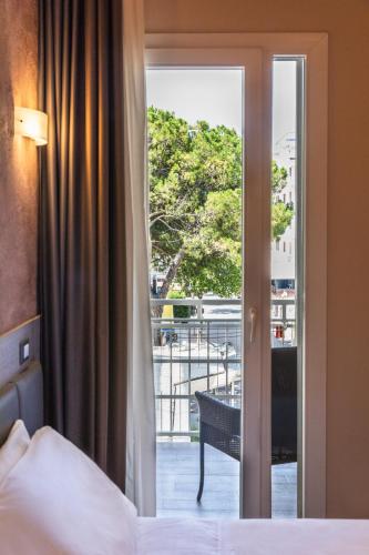 a bedroom with a door open to a balcony at Hotel Helvetia in Lido di Jesolo