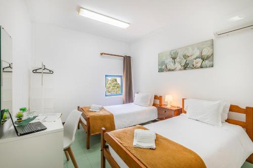 a room with two beds and a desk with a laptop at HI Faro – Pousada de Juventude in Faro