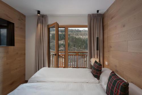 a bedroom with a bed and a large window at Residence Stella Alpina in Santa Cristina Gherdëina