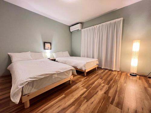 two beds in a room with wooden floors at 内町3階 高松中心地 広いメゾネット貸切 2ベッドルーム 最大4名 in Takamatsu
