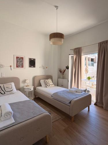 a bedroom with two beds and a large window at Sitia Heights Apartment - Central Sea View in Sitia