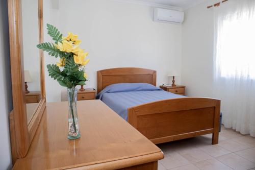 a vase with yellow flowers on a table in a bedroom at Villa BelaVista with Private Pool in Ferragudo