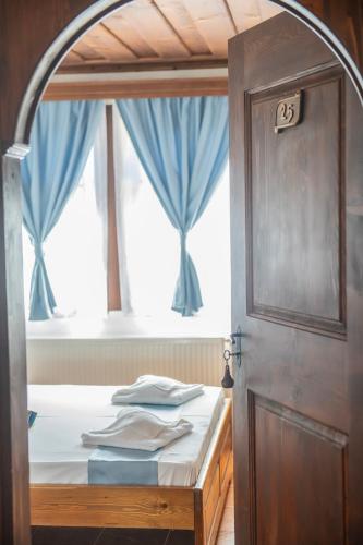 a bedroom with a bed and a window with blue curtains at Хотелски комплекс Усоето in Elena