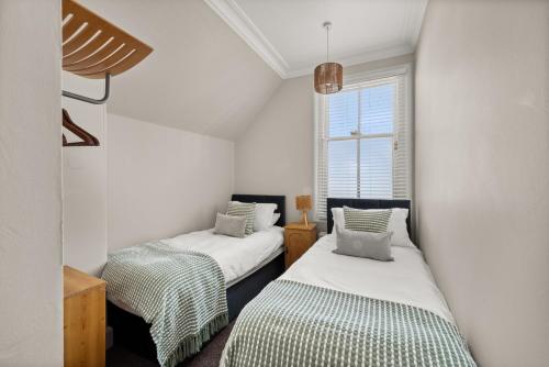 two beds in a small room with a window at Heywood Cottage in St. Andrews