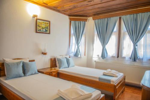 a bedroom with two beds with blue curtains and a window at Хотелски комплекс Усоето in Elena