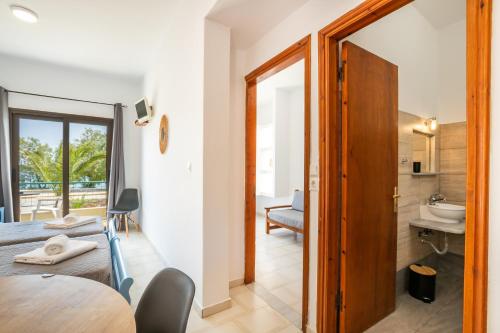 a room with a bed and a table and a bathroom at Sun Beach Apartments in Karpathos