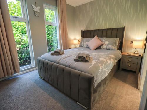 a bedroom with a large bed with two hats on it at Badgers Hollow Lodge in Windermere