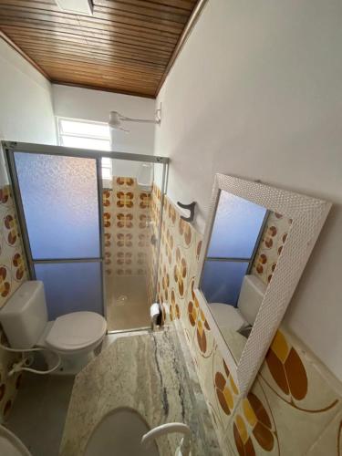 a bathroom with a toilet and a glass shower at Pousada Tapuia in Porto Seguro