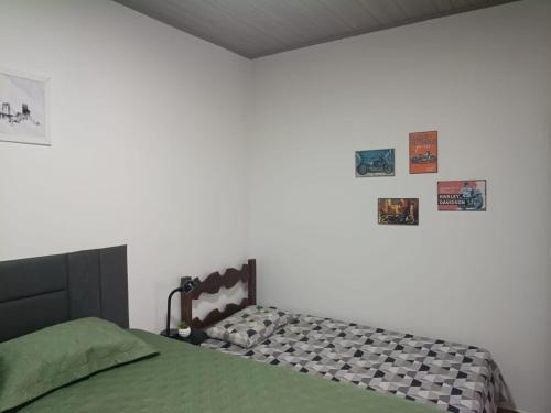 a bedroom with a bed with green sheets and pictures on the wall at Casa no centro de Brumadinho in Brumadinho