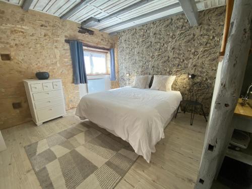 a bedroom with a white bed and a stone wall at Les Gîtes de Leymandie in Saint-Avit-de-Vialard