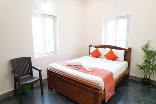 a bedroom with a bed and a chair and windows at Unique3 in Yercaud