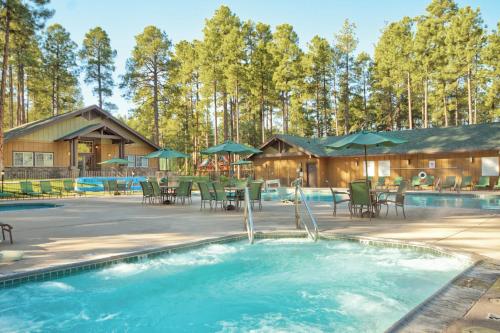 a pool with chairs and umbrellas in front of a house at Pinetop Resort Studio Apartment in Pinetop-Lakeside