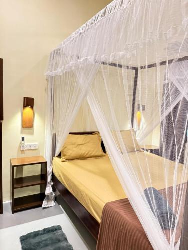 a bedroom with a bed with a mosquito net at Ocean Bliss in Pottuvil