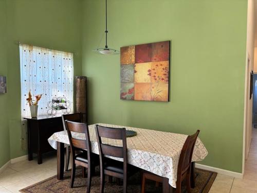 a dining room with a table with chairs and a painting at Right Direction Rentals Carnoustie Townhome in Port Saint Lucie