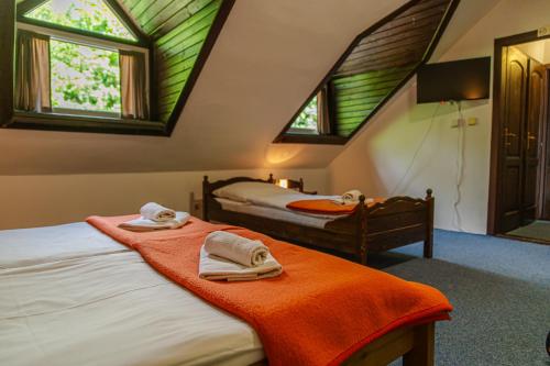 two beds in a room with windows and towels at Penzión Kúria in Dolný Kubín