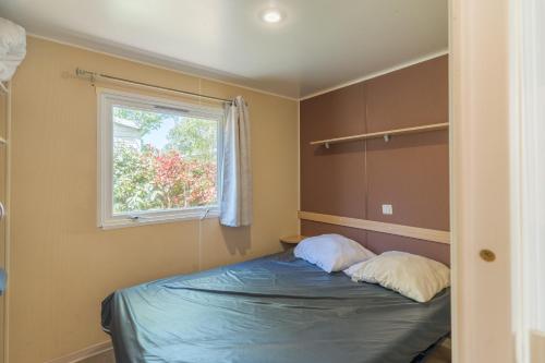 a bedroom with a bed with two pillows on it at Mobil-home Le 154 aux Iscles in La Roque-dʼAnthéron