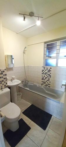 a bathroom with a tub and a toilet and a sink at Apartment on doonside Beach in Kingsborough